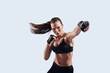 © G-Stock Faces - Full of strength. Attractive young woman looking at camera and boxing while standing against grey background