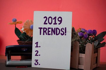 Text sign showing 2019 Trends. Business photo showcasing general direction in which something is developing or changing Flowers and writing equipments plus plain sheet above textured backdrop