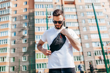 Canvas Print - Stylish bearded hipster in the at the city in a white T-shirt with waist bag