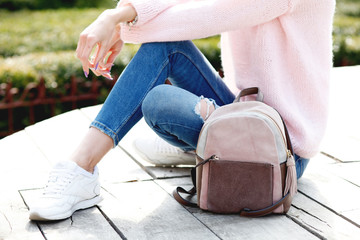  young hipster woman wearing casual outfit and leather backpack. Pink pullover and blue denim clothing in trendy style. 