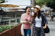 © PR Image Factory - Young asian female friends walking around small town in russia. happy girls traveler talking and carry coffee to go in hands shopping relax in outdoor holidays market on sunny day in spring.