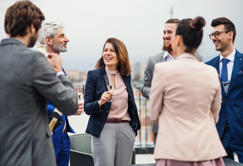 A group of joyful businesspeople having a party outdoors on roof terrace in city.