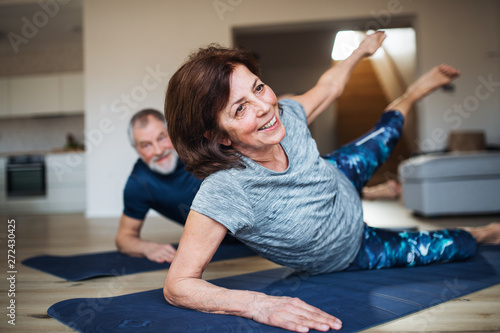 Cuadros en Lienzo A senior couple indoors at home, doing exercise on the floor.
