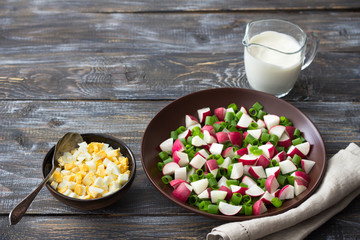 Wall Mural - Fresh radish salad with green onions on a wooden background, rustic style