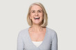 © fizkes - Headshot happy aged female laughing posing on grey studio background