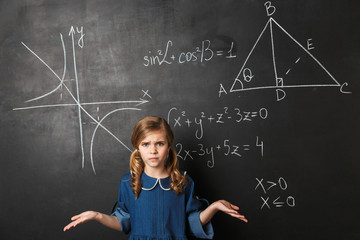 Smart little schoolgirl standing at the blackboard