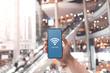 © oatawa - Hand holding smartphone with free wifi icon on blurred shopping mall background.