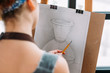 © golubovy - Art studio. Closeup back view of lefthanded painter measuring proportions with pencil in drawing vase.