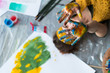 © golubovy - Fun leisure. Top view of creative female artist lying down on floor showing hands dirty with colorful paint. Blur background.