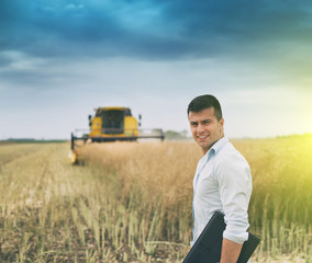 Canvas Print - Businessman with laptop in front of combine harvester