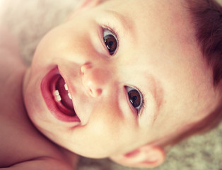 childhood, babyhood, emotions and people concept - close up of happy little baby boy or girl face