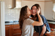 © guille Faingold/Stocksy - Happy kissing girls in kitchen