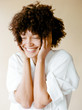 © Kayla Snell/Stocksy - Portrait of smiling mixed race young woman with Afro