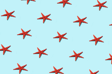 Trendy sunlight Summer pattern made with red starfish on bright light blue background. Minimal summer concept.