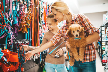 Mother and daughter with their poodle puppy in pet shop.