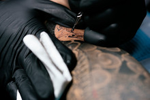 Closeup Of Asian Tattooer Makes A Tattoo