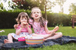 © Lea Csontos/Stocksy - Siblings sitting in a backyard having some snacks and fruits