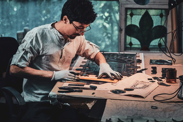 Wall Mural - Diligent restorer in glasses is counting right amount for stained glass at his own workshop.