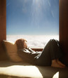 © Trinette Reed/Stocksy - Woman relaxing in cabin on mountain above the fog/ clouds in California