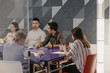 © Boris Jovanovic/Stocksy - Group of people having a meeting in the modern office, woman using a mobile phone
