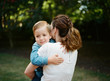© Jakob Lagerstedt/Stocksy - Adorable young boy peeking over the shoulder of his mother