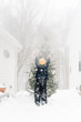 © L?a Jones/Stocksy - boy putting light up on Christmas tree in the snow