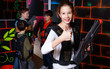 © JackF - Cheerful teen girl standing with laser pistol in dark lasertag room during game with friends