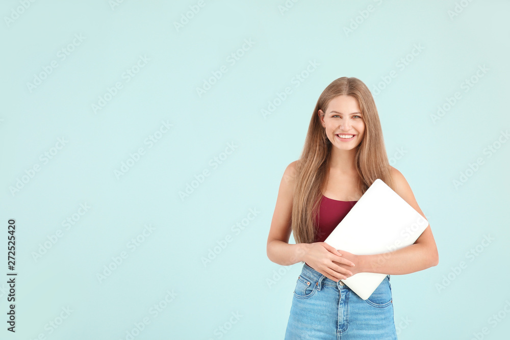 Beautiful young woman with laptop on color background