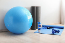 Set Of Sports Equipment With Fitness Ball And Bottle Of Water Near Light Wall
