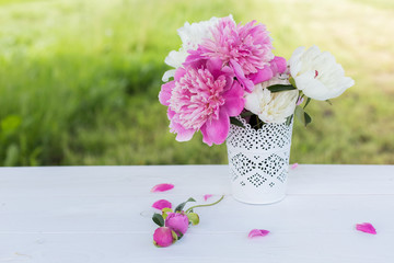 Beautiful soft pink peonies in vase on white wooden background outdoors. Summer flowers in blossom. Nature, fresh pink flowers concept