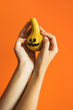 Female Hands Holding Small Halloween Cute Pumpkin On Orange Background