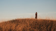 © brkati krokodil/Stocksy - Wide Shot Of A Woman In The Field Against The Blue Sky