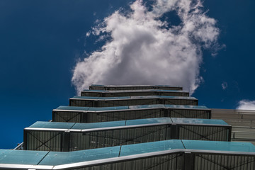 Business building with metal emergency ladder / fire escape in modern office buildings with repeating structure and reflected sky and clouds.