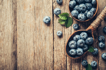 Blueberries in wooden spoon on old wood table. Healthy eating and nutrition concept.