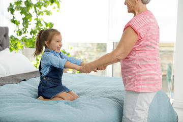 Poster - Cute girl and her grandmother playing together at home