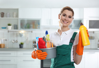 Canvas Print - Portrait of young woman with basin of detergents and bottle in kitchen. Cleaning service