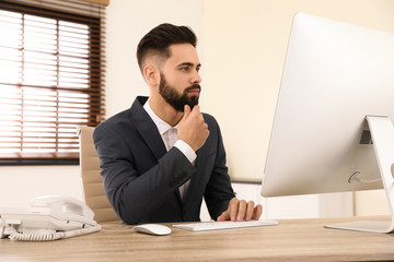 Wall Mural - Handsome businessman working with computer at table in office