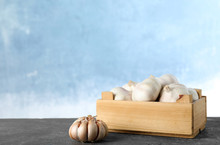 Wooden Crate Full Of Fresh Garlic On Table Against Color Background, Space For Text