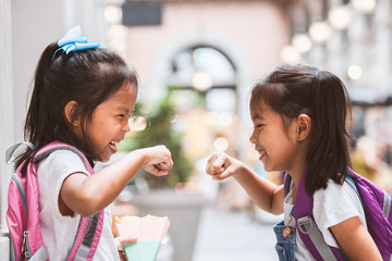 Wall Mural - Back to school. Two cute asian child girls with school bag playing together after school in the school