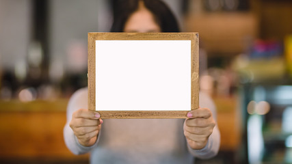 woman holding blank wooden frame in coffee shop