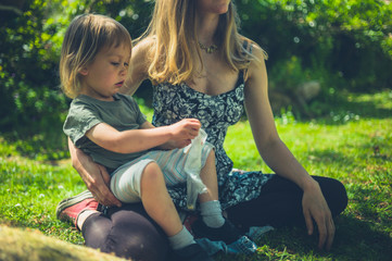 Mother and toddler sitting on grass in park