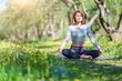© Sergey - Picture of woman doing yoga sitting in lotus position on blue rug in woods