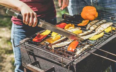 young woman cooking organic vegetables at barbecue dinner outdoor - couple grilling peppers and aube