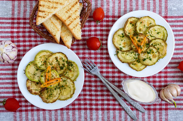 Wall Mural - Tasty fried zucchini slices on a plate with sauce on a wooden table. Picnic snack. Rustic style. Top view, flat lay.