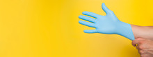 Doctor Putting On Protective Blue Gloves Isolated On Yellow Background. Copy Space
