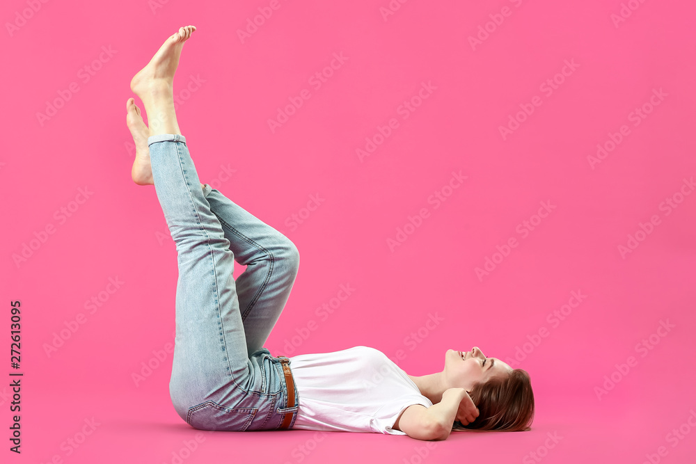 Stylish young woman in jeans on color background