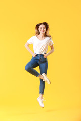 Wall Mural - Jumping young woman in jeans on color background