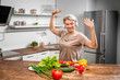 © Pixel-Shot - Mature woman dancing while cooking in kitchen