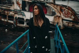 Fototapeta Krajobraz - Woman posing on bridge against the background of an old rusty ship.