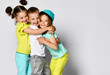 © FAB.1 - Studio portrait of children on a light background: full body shot of three children in bright clothes, two girls and one boy. Triplets, brother and sisters. hugging on camera. Family ties, friendship